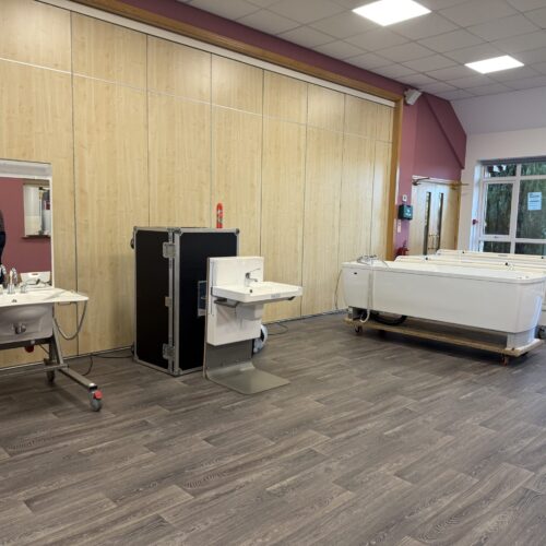 LB Bathing Assessment A photo of a selection of accessible baths and accessible sinks on display in a church hall set up for a client demonstration.