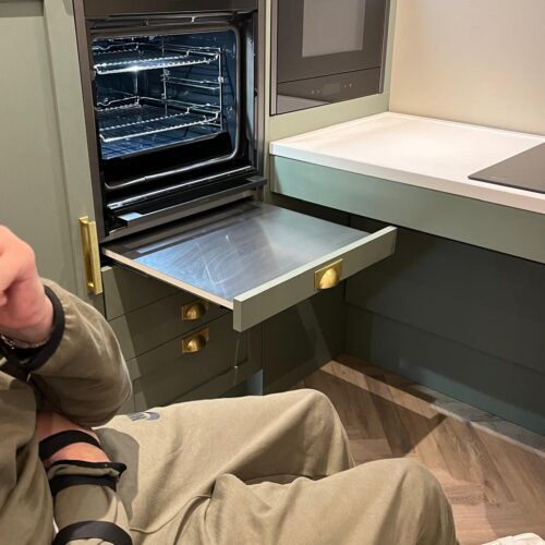 Oven, counter top and microwave A young man looking at accessible kitchen options. An oven with pull out surface at the bottom for resting pots, a low height countertop with room for wheelchair underneath and a microwave oven with level access to the countertop.